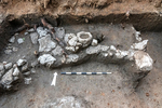 Grave 110 covered with stones, among them a grinding basin in secondary use, looking north.